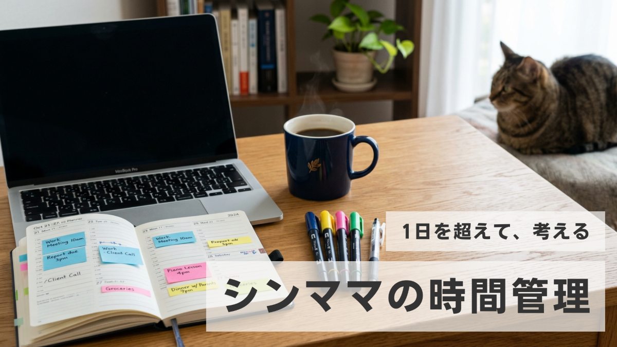 色分けされた週間手帳とノートパソコン、傍らでくつろぐ猫